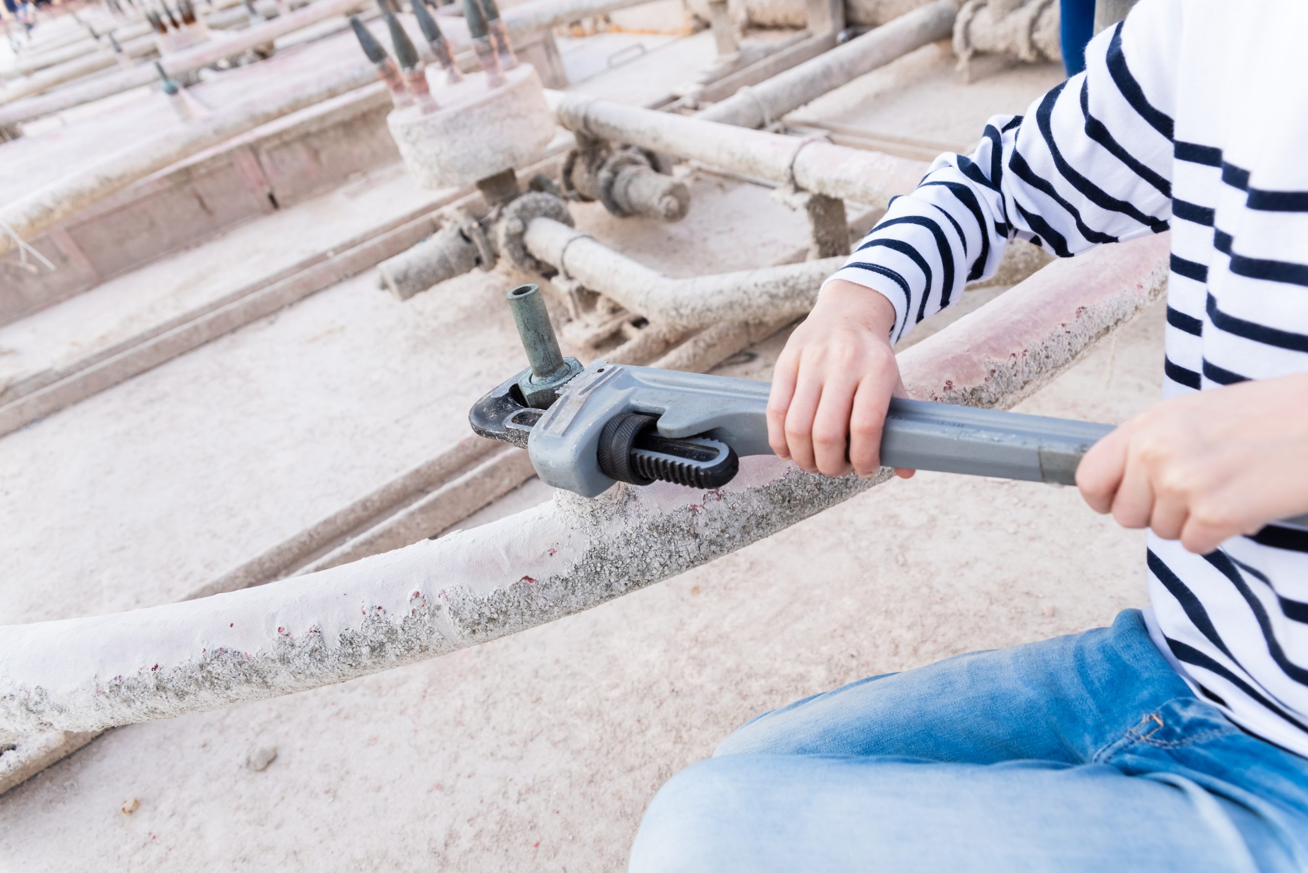 Children using a heavy-duty straight pipe plumbing wrench to repair a pipe.